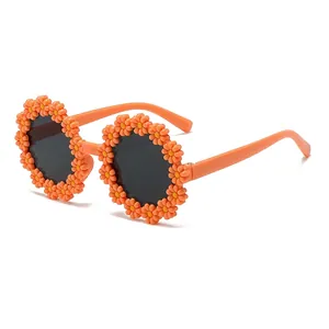 Daisy flower children sunglasses with orange frame and dark round lenses on white background