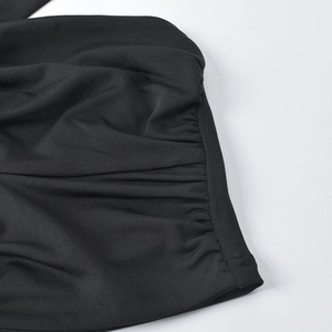 Close-up of ruched side detailing and stitching on black knit cropped top