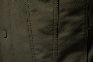 Vista macro del tessuto twill verde oliva con cuciture doppie rinforzate sulla giacca