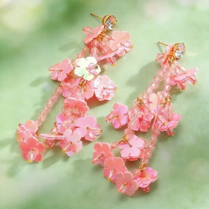 Detailed close-up of pink layered flower earrings with gold finish and sparkling crystals