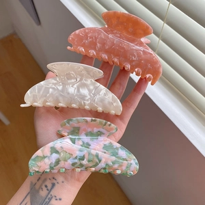 Détails de grandes pinces à cheveux en acétate aux motifs marbrés rose, crème et vert