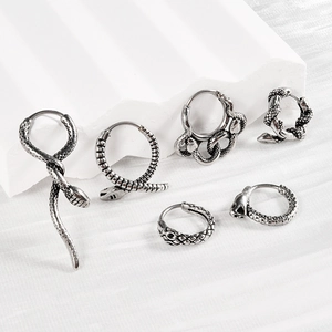 Vintage silver snake earrings set with punk style heart hoops on a stone display