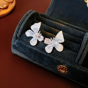 Close-up of butterfly stud earrings with sparkling crystals on black velvet