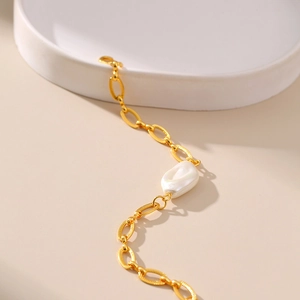 Macro-opname van de gouden getextureerde ketting en een barokke parel op de armband