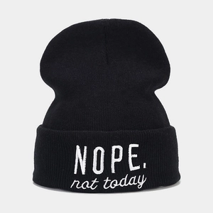 Gros plan de la broderie 'NOPE. not today' blanche sur le revers du bonnet noir