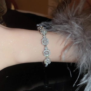 Detailed view of emerald geometric bracelet with diamonds on woman wrist