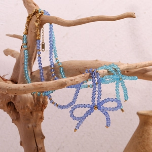 Artistic display of blue crystal beaded necklace with bow pendant on a wooden stand