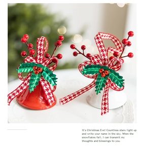 Detail of red and white Christmas bell ornaments with ribbon and berry on white tray
