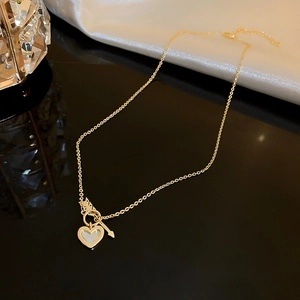 Detail of gold heart pendant with white shell inlay and arrow T-bar toggle clasp