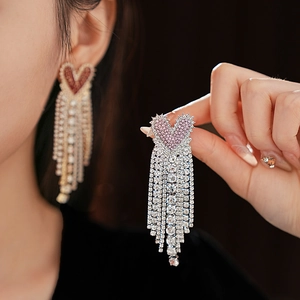 Close-up of sparkling heart-shaped stud earrings with elegant long tassel diamond fringe