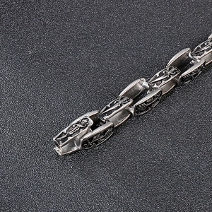 Macro detail of punk stainless steel bracelet showing embossed sword and cross motifs