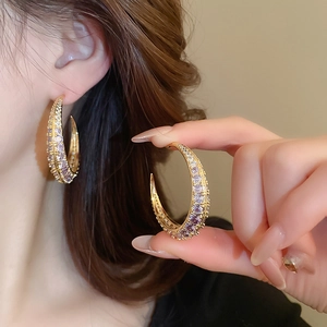 Detail of gold-plated C-shaped hoop earrings with lavender cubic zirconia pave stones