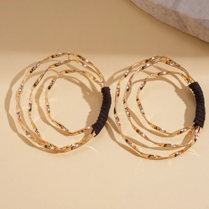 Close-up of geometric multi-layer gold earrings with hammered texture and black thread detail