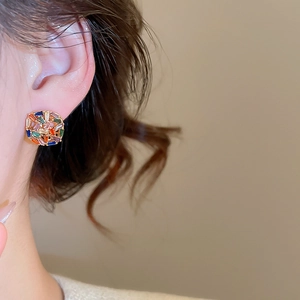 Macro shot of colorful zircon square stud earrings on ear with gold plating finish