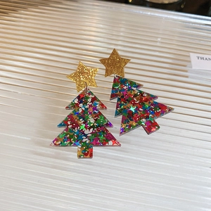 Macro shot of glittery Christmas tree earrings with golden stars and colorful sequins