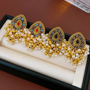 Gros plan de boucles d'oreilles vintage avec pierres colorées et glands de perles blanches