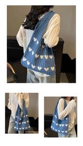 Detalle de bolso de hombro de punto azul con patrones de corazones blancos y trenzado