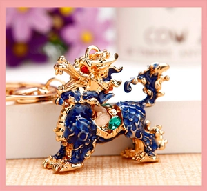 Close-up of golden dragon keychain with blue enamel and sparkling inlaid gemstones