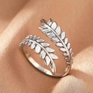 Macro view of vintage silver olive leaf ring on elegant champagne satin fabric background