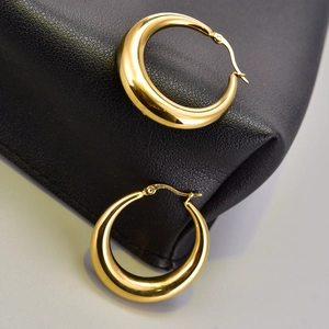 Detalle de pendientes de aro gruesos de oro de 18K con forma de luna sobre cuero negro
