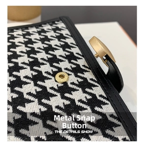 Macro shot of houndstooth fabric texture and golden snap button on the wallet