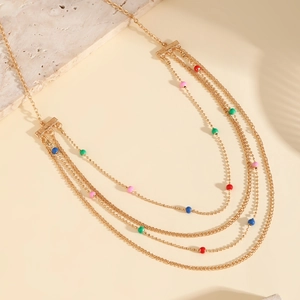 Detail of layered gold-plated necklace featuring colorful pink, green and blue beads