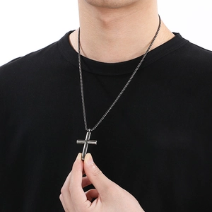 Close-up of vintage dark grey stainless steel cross necklace on a person wearing black