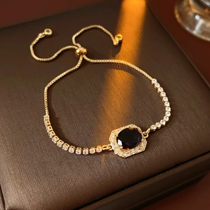 Close-up of adjustable gold bracelet with dark oval gemstone and micro-paved zircons