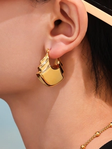 Gros plan de boucles d'oreilles géométriques en or 18K poli avec design étagé brillant
