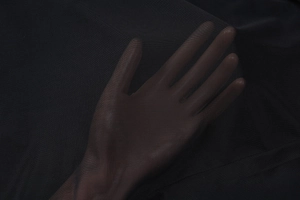 Gros plan sur le tissu en maille noire montrant sa texture translucide et ses détails