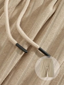 Detail of beige textured waffle knit shorts with adjustable drawstring and elastic waistband