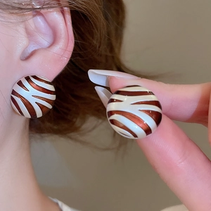 Detailed close-up showing brown and white zebra pattern enamel earrings on ear