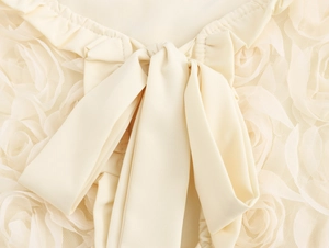 Close-up of cream cardigan featuring a large bow and 3D floral lace embroidery details