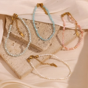 Close-up of colorful natural stone anklets with 18K gold plated clasps on stone