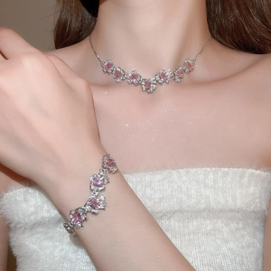 Detail of silver necklace and bracelet set with pink zircon square flower charms on a model