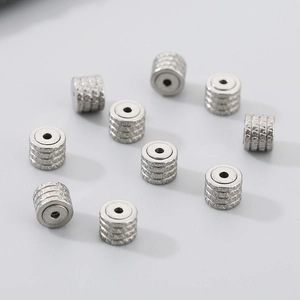Macro detail of silver stainless steel cylinder beads with horizontal engraved textures