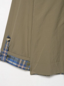 Detailed close-up of olive green woven fabric with plaid lining and amber button
