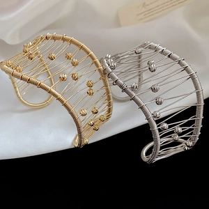 Detailed view of woven metal mesh open bracelets in gold and silver finish