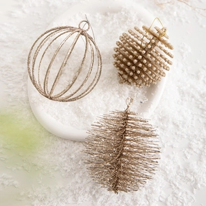 Golden glitter Christmas ornaments with pine cone and wire ball on white artificial snow
