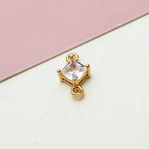 Macro shot of gold-plated geometric rhombus pendant with clear cubic zirconia and dual loops