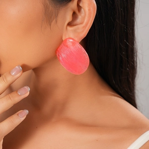 Close-up of pink oval resin earring with striped texture worn by a model