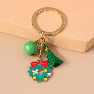 Close-up of Christmas wreath keychain with green bell and tassel on beige background