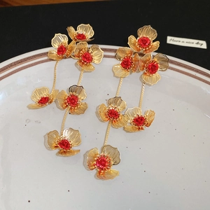 Detail shot of vintage hollow gold flower earrings with red roses and long tassels