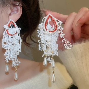 Close-up of vintage lace earrings with red rhinestones and white teardrop pearls