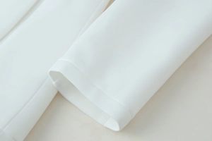Detailed view of high-density white fabric texture and precise stitching on the sleeve cuff