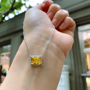 Detail of silver necklace with square yellow gemstone pendant on female model