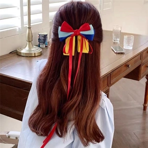 Detailed back view of a red blue and yellow bow hair clip with ribbons on long hair