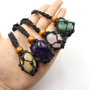 Detail of four colorful natural raw crystals in hand-woven black mesh necklace pouches