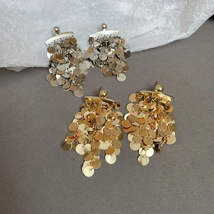 Close-up of gold and silver sequin tassel earrings with mirror-like metallic shine