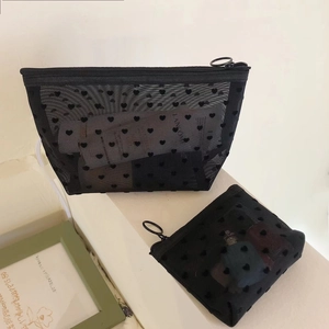 Close-up of black mesh makeup bags with velvet heart patterns and large metal zippers